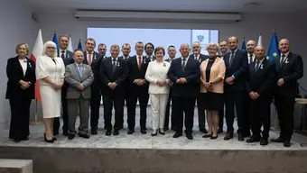 Grupa ludzi ubranych formalnie stoją obok siebie pozując do zdjęcia