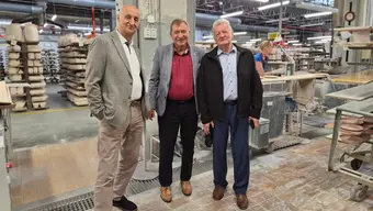 trzech mężczyzn stoi obok siebie w tle zakład produkcyjny płytek ceramicznych
