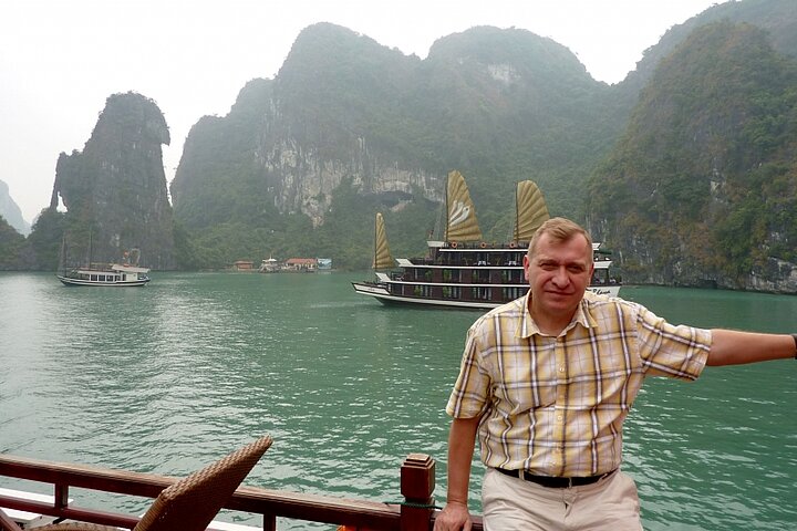 Mężczyzna w koszuli pozuje na tle jeziora i skał w mglisty dzień