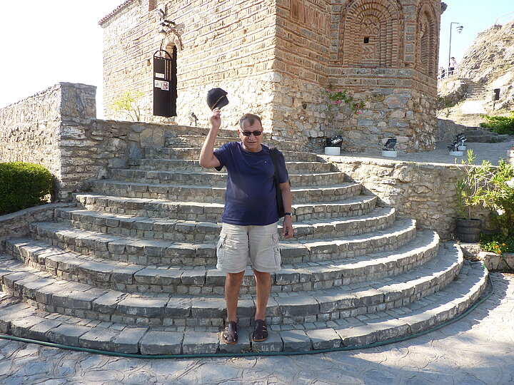 Mężczyzna ubrany casualowo pozuje na tle kamiennego budynku