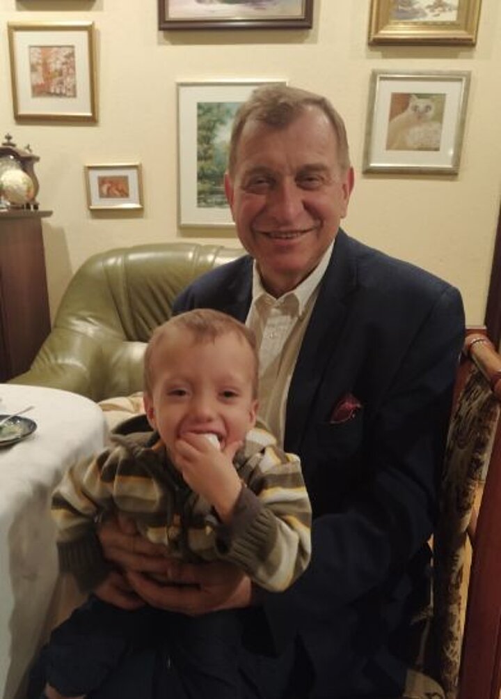 Mężczyzna siedzi przy stole i trzyma na kolanach małego chłopca 