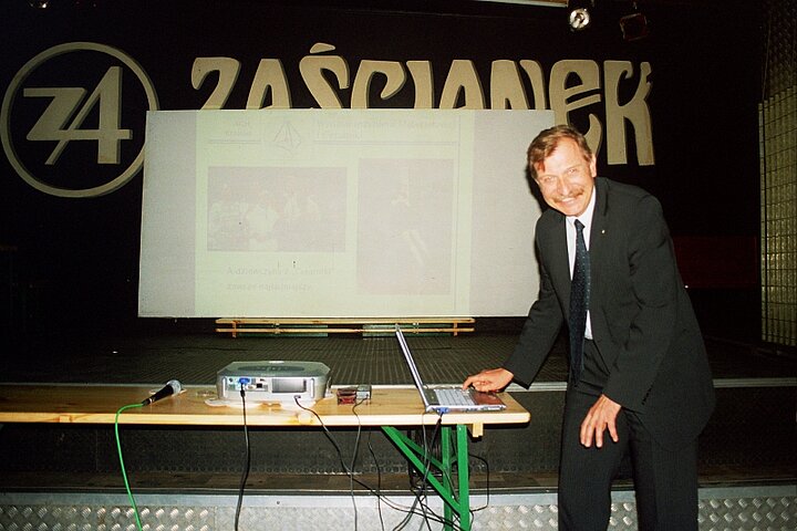 Mężczyzna ubrany w garnitur pochyla się nad stołem