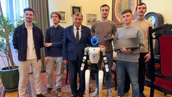 grupa mężczyzn stoi obok siebie między nimi jest humaniodalny robot
