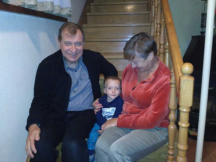 Mężczyzna, kobieta i mały chłopiec ubrani casualowo siedzą na drewnianych schodach