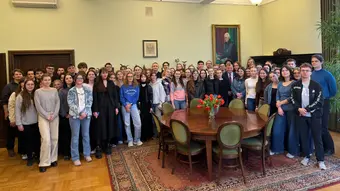 grupa młodych ludzi zebranych w sali pozuje do zdjęcia