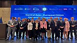 grupa ludzi ubranych formalnie stoi obok siebie w tle duży ekran