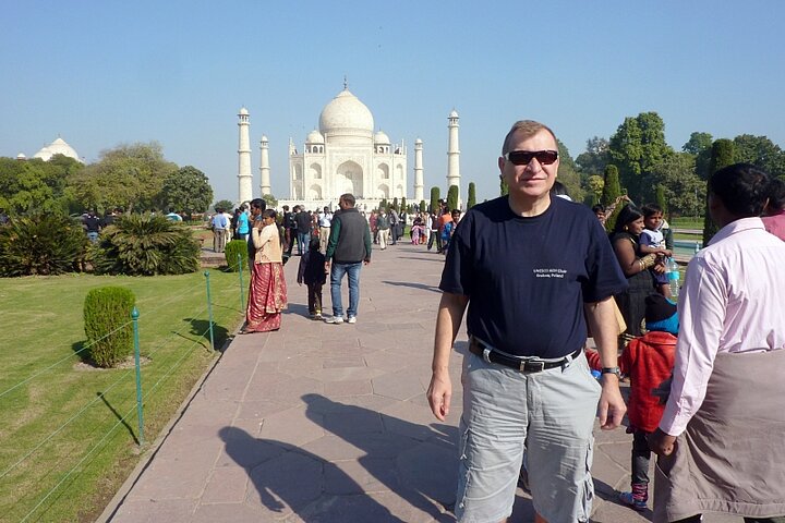 Mężczyzna ubrany casualowo pozuje na tle pałacu