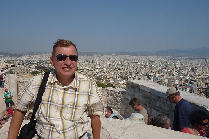 Mężczyzna ubrany casualowo pozuje na tle panoramy miasta