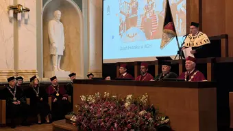 grupa osób ubranych w togi siedzi w ławach